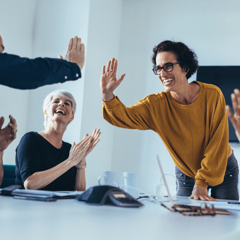 A smiling team high-fiving | When Do Facebook Ads Start Working?